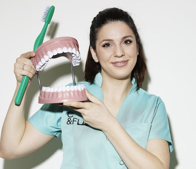 Wir sind für Sie da | Dr. Dr. Felix Wick | Assistentin mit Zahnmodell und Zahnbürste zur Demonstration der Putztechnik.